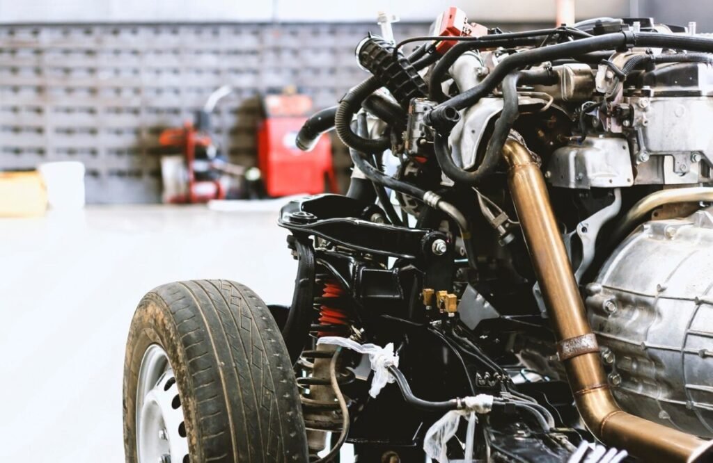 Exposed car engine, exhaust, and suspension on rolling chassis in garage