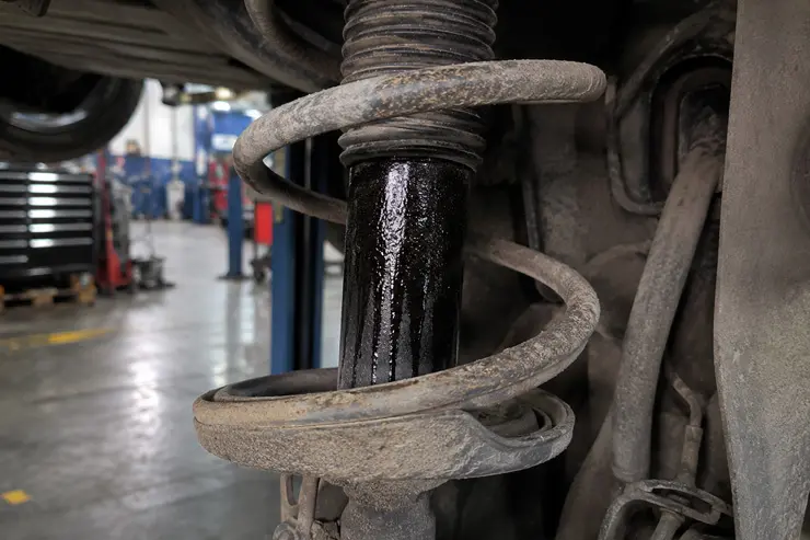 Worn shock absorber with visible oil leak requiring Shock Absorber Replacement