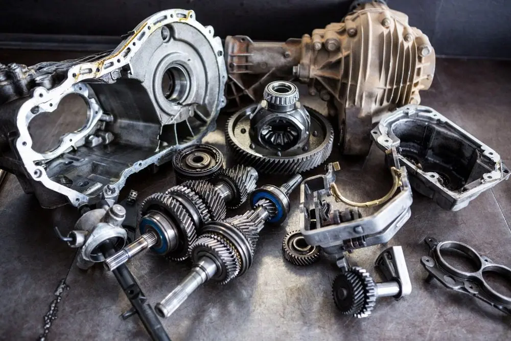 Disassembled car transmission with gears, shafts and differential parts on workshop table